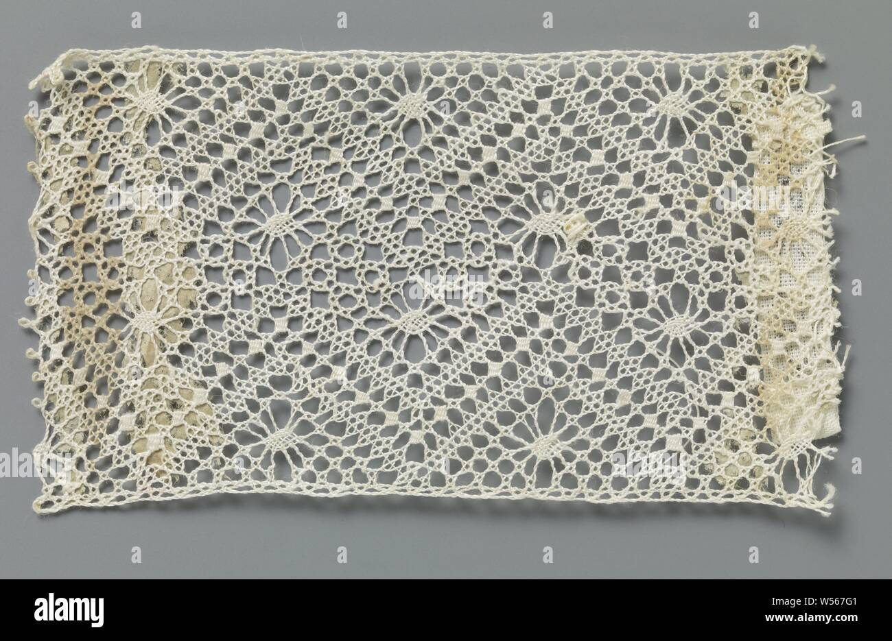 Bobbin-lace insert with two zigzag lines, Natural-colored bobbin lace strip: lace-up. The repeating pattern consists of two parallel zigzag paths with a center line of concatenated fine diamonds made in form. At the top and bottom of the zigzag webs, a sling is used, and between the zigzag webs a twisted cross-streaked soil is used. There are pointed oval spots in the grounds. The top and bottom of the strip are finished straight., anonymous, Russia (possibly), c. 1900, linen (material), torchon lace, l 8 cm × w 4.5 cm ×, 2.6 cm Stock Photo