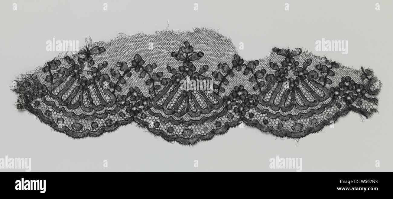 Fragment of bobbin lace with inverted fan-shaped motif in scallop edge, Fragment of black bobbin lace: Chantilly lace. The fragment is elongated in shape, with a scalloped edge on one long side, the other sides are cut off irregularly. The repeating pattern consists of a diamond-shaped configuration of four rosette flowers, under which hangs a more or less fan-shaped motif. The successive impellers are connected by arcs with leaves. Under each arch there are four rosette flowers again, which form the suspension points of the continuous decorative band that also forms the shell edge. Stock Photo
