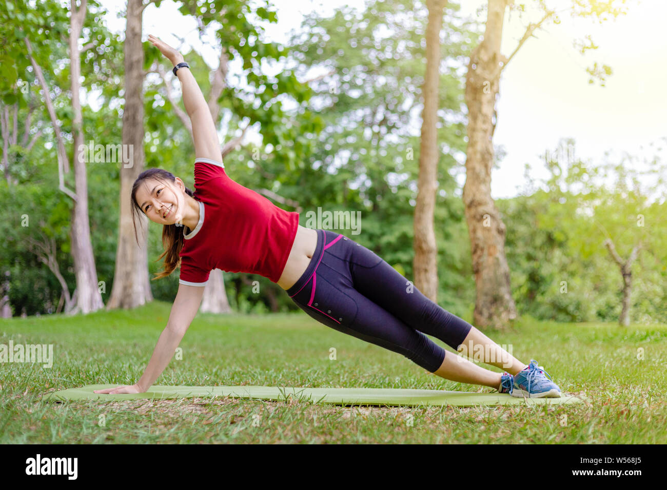 Side view of happy young athlete woman stretching her body before and ...