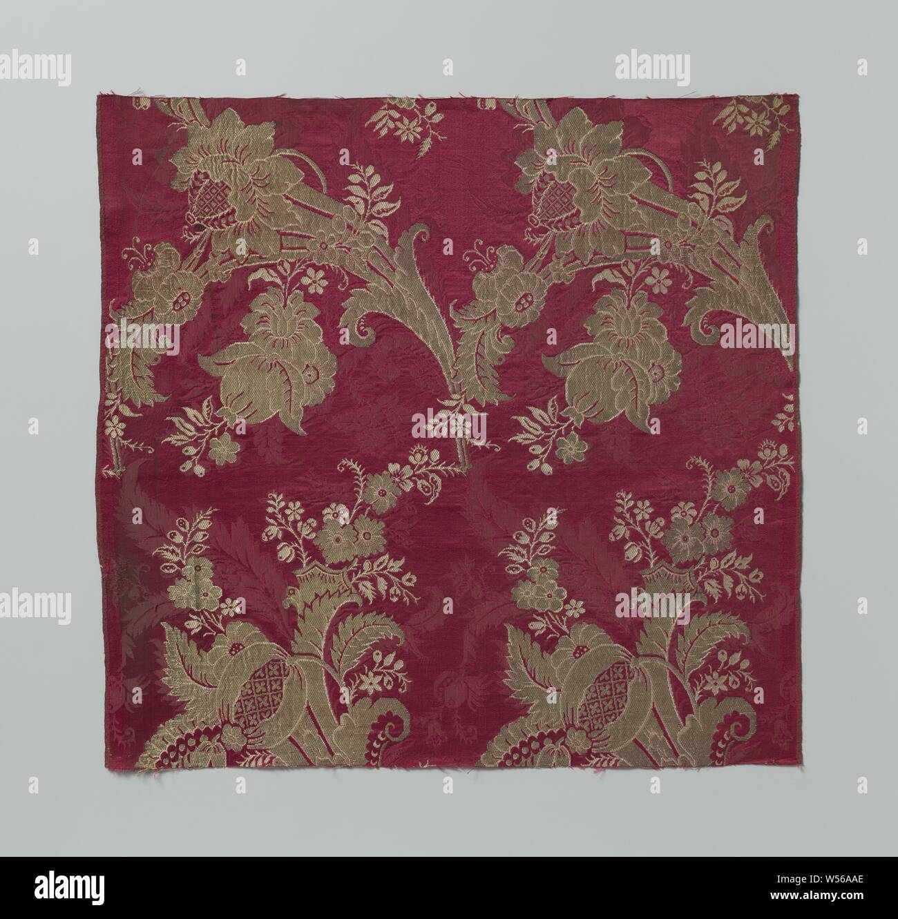 Fragment of carmine-red damask with golden silk fabric with a pattern of stylized leaves and flowers with curved umbels of flowers, leaves and fruits, A fragment of carmine-red damask with a pattern of stylized leaves and flowers, on which silver wire pattern of rows of flower bulbs curving left and right alternately filled with pomegranates and rosette flowers with a pear-shaped heart. Silver and white., anonymous, Netherlands, c. 1695 - c. 1760, silk, damask, h 49 cm × w 51.5 cm w 25.5 cm w 0.4 cm Stock Photo