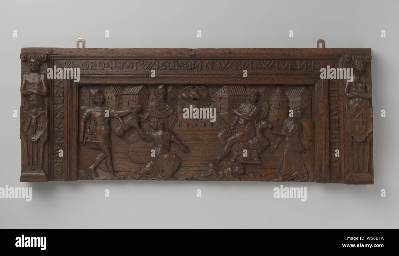 Fragment of a chest, the so-called front board, Part of the front board of an oak box. The corner posts have hermcaryatides with coats of arms, on the one the crucified Christ with the lance in the side wound and the initials K. The front plate is adorned in rough stitching with a relief. In the middle a large lion mask. The frame says: 'Koninck Salemo arranges twischen twen wiven that deit men eme'., anonymous, Noord-Duitsland, c. 1600 - c. 1625, wood (plant material), oak (wood), h 31 cm × w 79.5 cm × d 6.5 cm Stock Photo