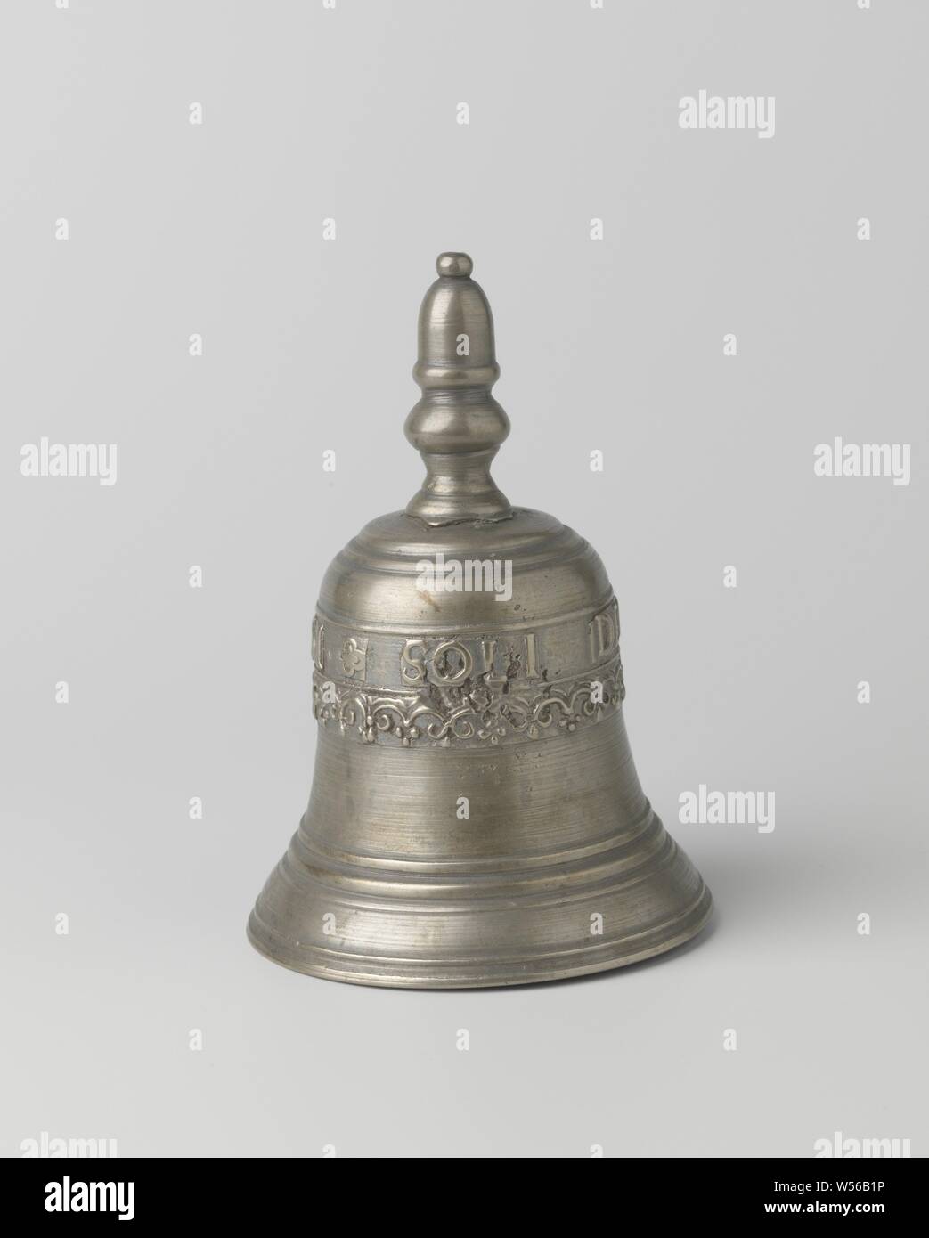 Table bell with inscription: SOLI DEO GLORIA 1661, The object is composed of four parts: the bronze bell and the bronze handle embossed on it, the iron ear and the wrought iron clapper. The bell is bell-shaped and has a profiled edge. At the top the inscription SOLI DEO GLORIA 1661 and a frieze of bows. The handle is button-shaped with an acorn on top., anonymous, Netherlands, 1661, bronze (metal), iron (metal), founding, h 14.7 cm × d 10.2 cm Stock Photo