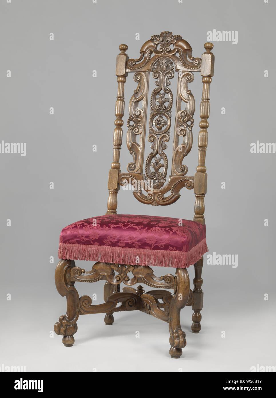 Chair with angled front legs, X-shaped cross, upholstered with flower pattern, Walnut chair, covered in bronze-colored pressed fabric flower pattern. The chair has angled front legs in the shape of broken S-volutes and rests on lion's claws that include spheres. The X-shaped cross has broken S-volutes, as well as the front cover. There is a button at the intersection. The high, open-worked back also shows S-volutes. The elongated center piece is decorated with circle and rosette in the middle and above and below with acanthus leaves and rosettes., anonymous, Netherlands, 1685 - 1700, walnut Stock Photo
