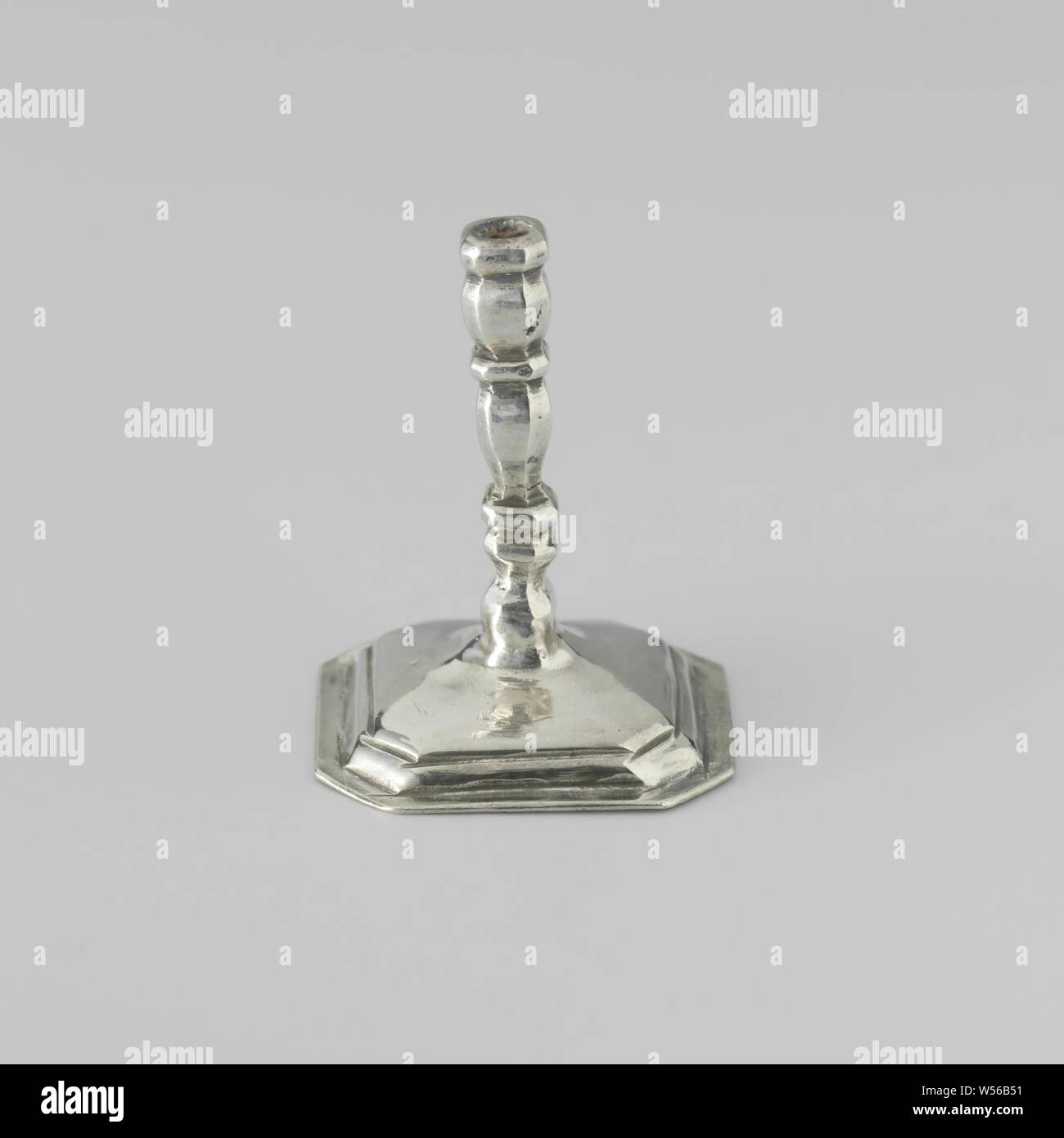 Candlestick, Candlestick on a square, arched base with beveled corners. The stem of the candlestick and the edge of the foot are profiled. The candlestick is marked: stk. = Amsterdam, mt. = Citroen 1975, nr. 970 and an ax, anonymous, Amsterdam, c. 1704 - c. 1734, silver (metal), l 2.8 cm × w 2.8 cm × h 3.6 cm Stock Photo
