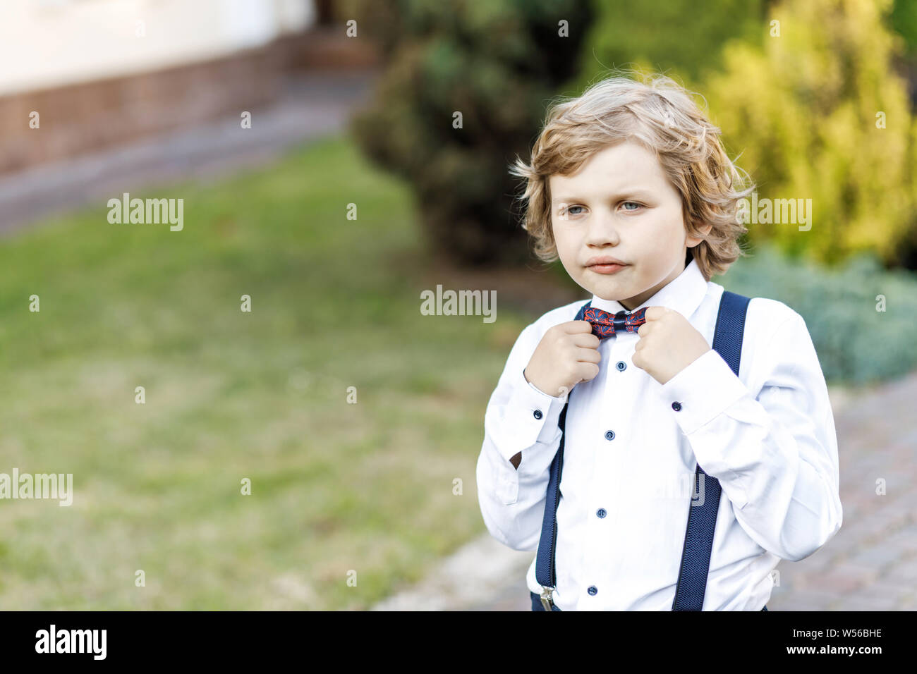 Cute blond guy, school year, dressed in school uniform, takes her time outdoors in between classes Stock Photo