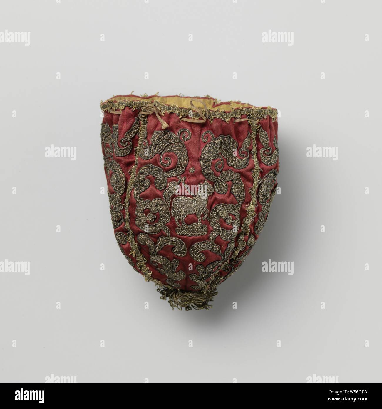 Bursa, dark red, decorated with ecclesiastical symbols in sewn-on gold thread, including Cross-bearing Lamb of God, composed of four parts. Decoration of sewn-on gold thread: twice a heart, a cross-bearing Lamb of God and a flamed globe on chalice, all within a floral frame. At the top a drawstring, at the bottom a tassel of gold thread. Lined with yellow silk., anonymous, Europe, c. 1600 - c. 1699, iron (metal), h 13 cm Stock Photo