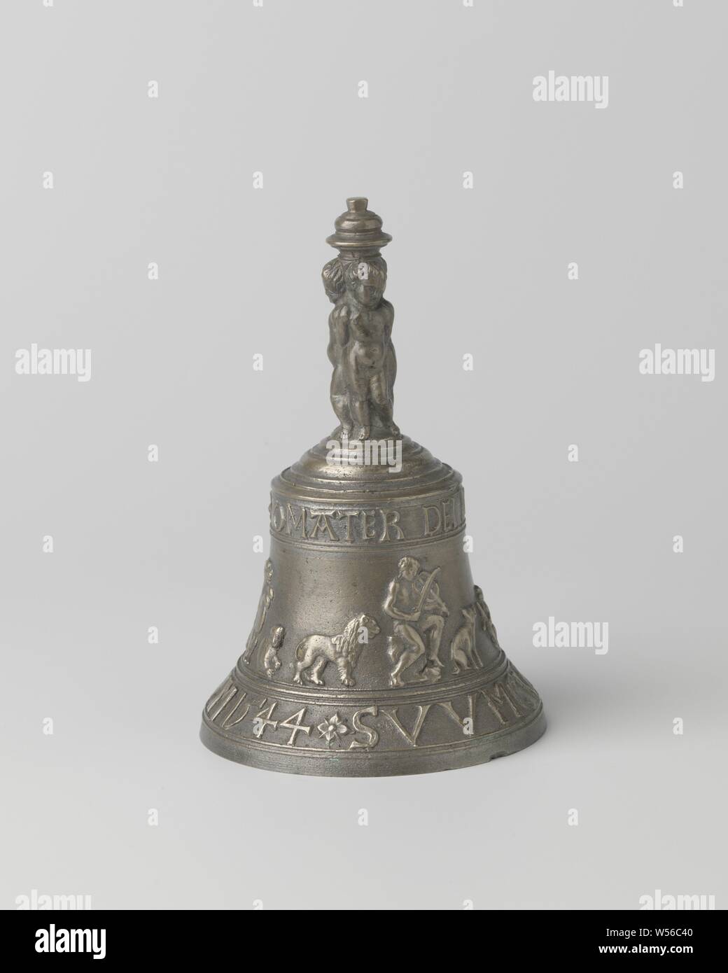 Table bell with inscription: ME FECIT PER IOHAN DE FINE Ao 1544 etc, The object consists of three parts: the bell-shaped bell with the handle, the iron eye and the iron clapper. On the lower edge of the bell the inscription: ME FECIT PER IOHAN DE FINE Ao 1544. Above, on the front and back, two medallions formed by wreaths, one showing the heads of a woman and a man with laurel wreath and the other showing a man's head. The wreaths are held up by one hand by putti, who point to high Renaissance vases with the other hand. Above the medallions and the two vases are ram heads, which are connected Stock Photo