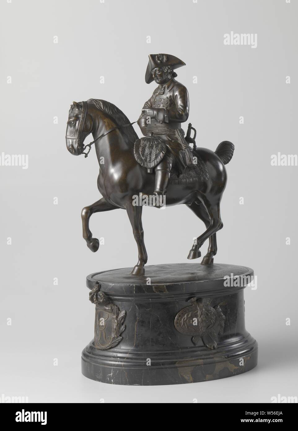 Statuette of Frederick the Great, King of Prussia Statue of Frederick the Great, King of Prussia, The king (1712-1786) sits on a step-by-step horse that has lifted the right foreleg and the left hind leg for a moment ground light, the head is turned slightly to the right. He holds the rein with one hand, while the other rests in the side. He wears a uniform consisting of a jacket with a jabot, gloves and boots, on the head a wig and, on the jacket, place the Order of the Black Eagle, a sash around the waist, a sword and a sword on the left. The saddle, with rider pistols on both sides in Stock Photo