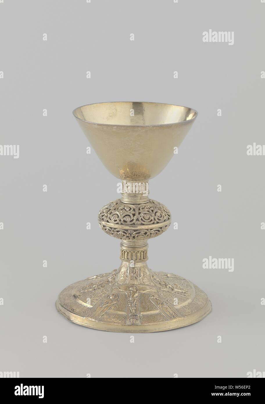 Chalice Chalice on a round base, decorated with a representation of Christ on the cross, Chalice of gilt silver, unadorned, funnel-shaped cuppa. On the round foot in stamping work: Christ on the cross between Mary and John and five sitting figures of saints. The nodus is adorned with ajour floral and vines ornament, the tribe has a round-arch frieze in filigree work both above and below the nodus, crucified Christ with Mary and John on either side of the cross, Holy Red, anonymous, Oost-Nederland, c. 1200 - c. 1299, silver (metal), gilding, h 18.5 cm × d 15.2 cm × w 462.0 Stock Photo