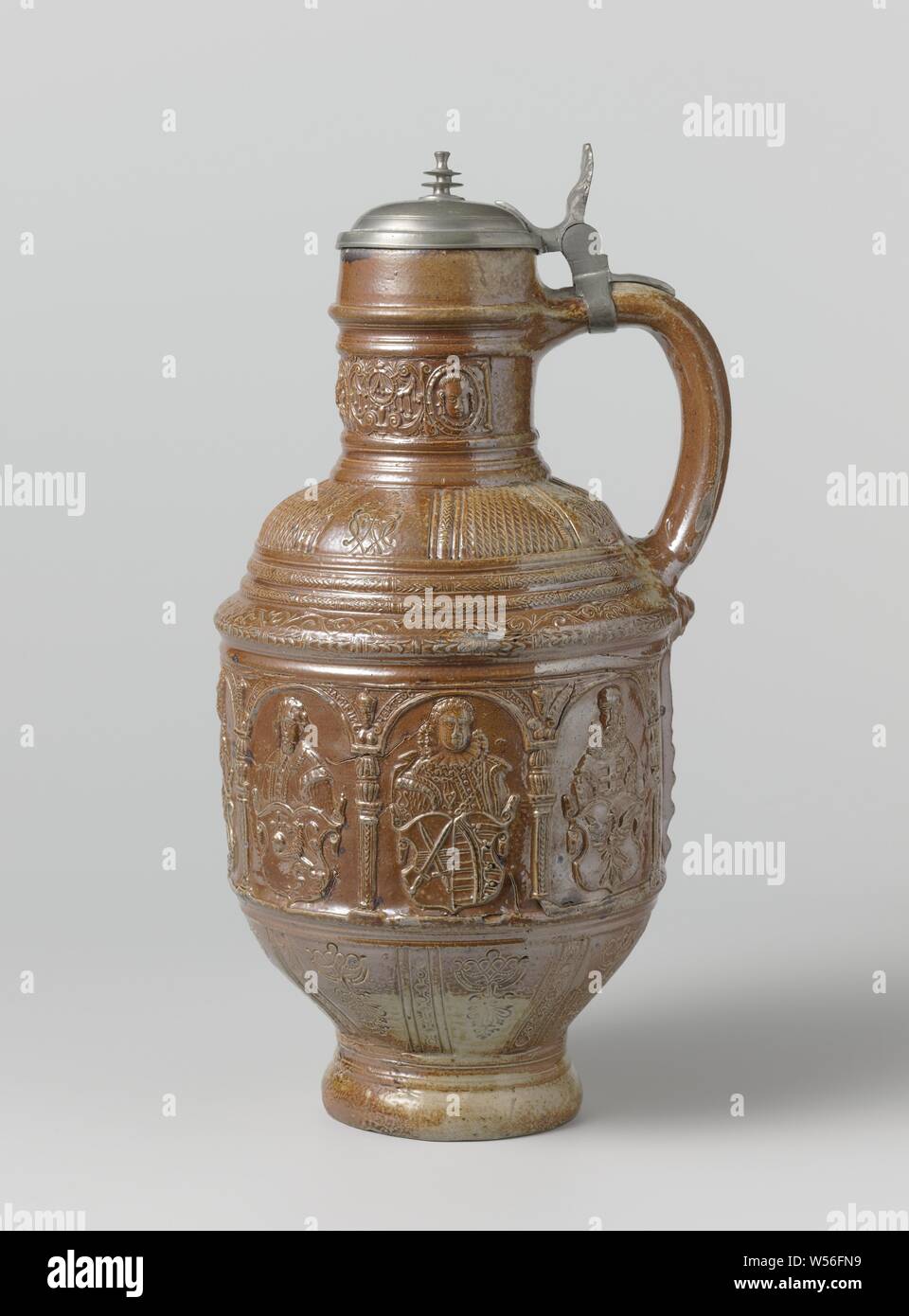 Jug with a representation of the electors, Stoneware jug on a high foot with a cylindrical body, round shoulder and wide neck. Profiles on the neck, body and foot. Covered with a brown engobe. On the belly in relief a printed and imposed band with bows. Under each arch is a Elector with his respective coat of arms (the Archbishops of Trier, Cologne and Mainz, the King of Bohemia, the Margrave of Brandenburg, Palzgraaf and the Duke of Saxony), with his title in the arc. In the leftmost box the date '1602'. The lower part of the abdomen is sloping towards the foot and has incised pockets Stock Photo