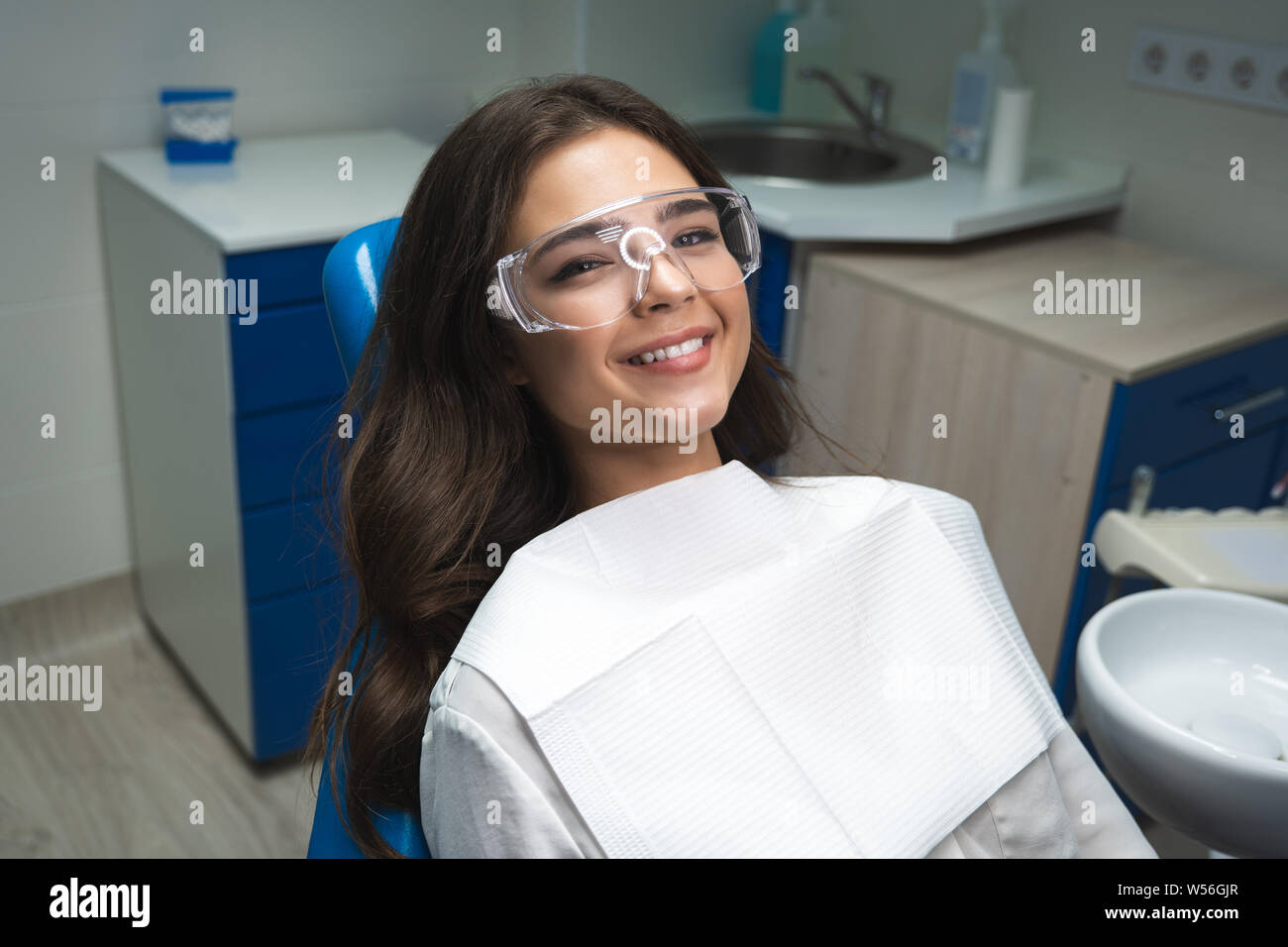 smiling young woman patient lying on dental chair wearing