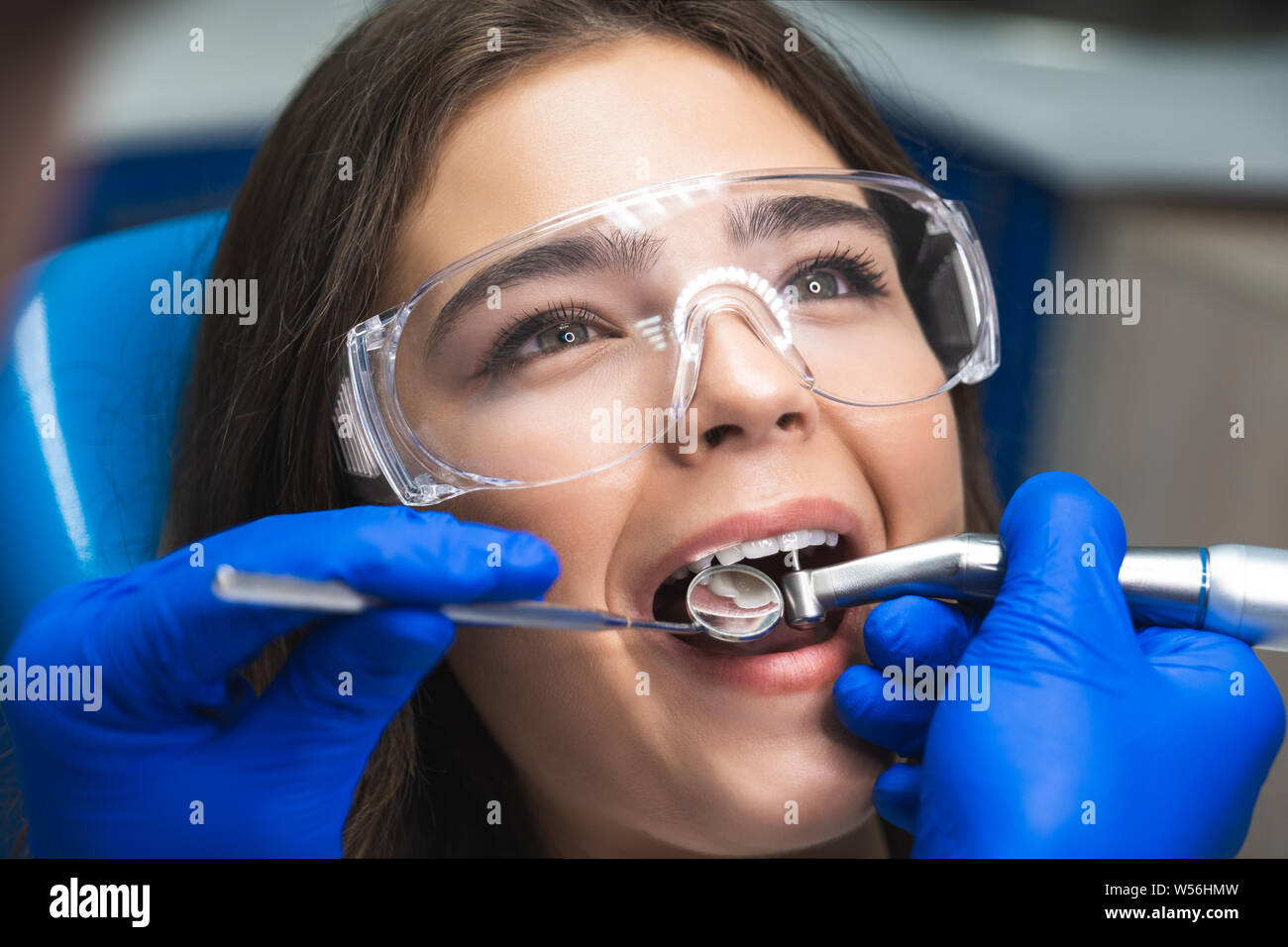young patient woman in safety glasses curing root canal in clinic close