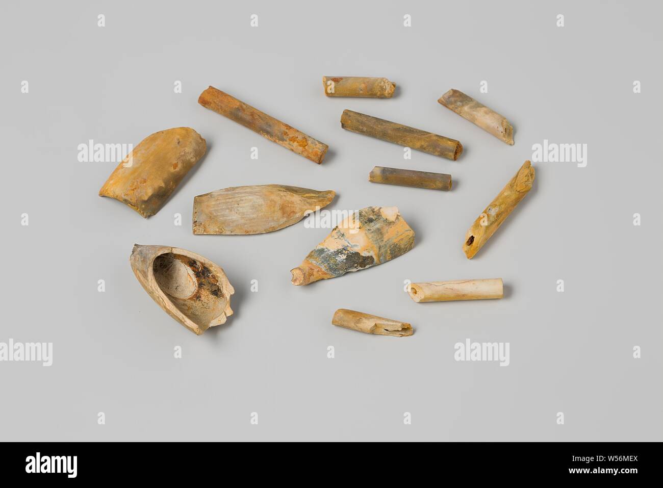 Pipe heads and stems from the wreck of the East Indies' t Vliegend Hart, Four fragments of heads of earthen Gouda pipes and eight pieces of pipe stem, yellow-blue-metallic discolored, Dutch East India Company Flying Heart (ship), Gouda, 1700 - 3-Feb-1735, pipe clay, l 3.8 cm × w 1.9 cm × d 2.1 cm × l 2.2 cm × d 0.6 cm Stock Photo