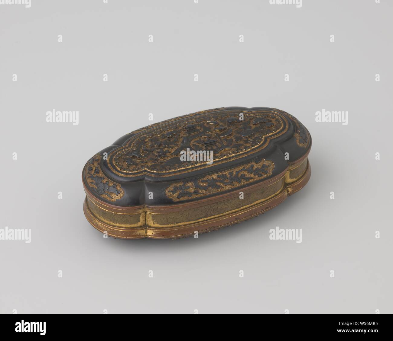 Suassa tobacco box, Oval, double-corrugated tobacco box with hinged lid, black and copper colored. Cartouches with plant and flower motifs on the edge of the lid and bottom, black on copper color. On the lid and on the bottom: large cartouche with Asian landscape: flowering trees with birds, houses and a figure in a boat with waving vanes, Tonkin, Dutch East India Company, 1700 - 1800, metal, gilding (material), gilding, h 3.8 cm × w 12.1 cm × d 6.4 cm × w 238 Stock Photo