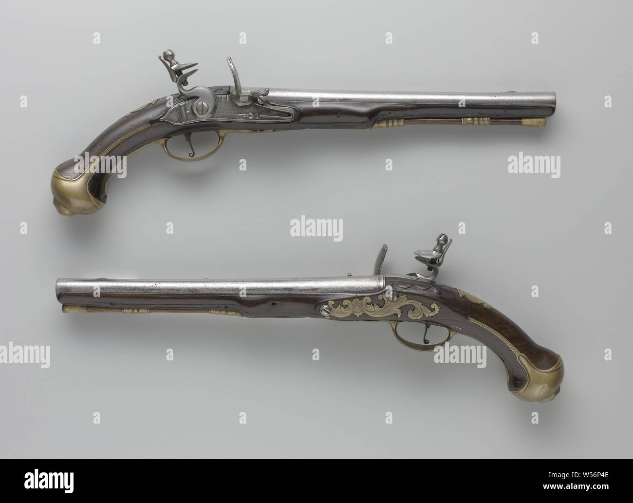 Flint gun, Part of a couple. The tail plate's tail has been kicked, unadorned except for an engraved strand of beads under the pan and the signature after. The round barrel is flattened on top and becomes wider at the trumpet, on the back a ring with a deep keep for the rear visor that extends to the tail of the barrel, iron visor grain, 142-A is stamped on the bottom with a mark in the shape of a chair under a crown. The flask of blackened walnut is easily cut. The previously gilded, yellow copper fittings consist of two loading rod sleeves in relief, the trigger guard, a symmetrical screw Stock Photo