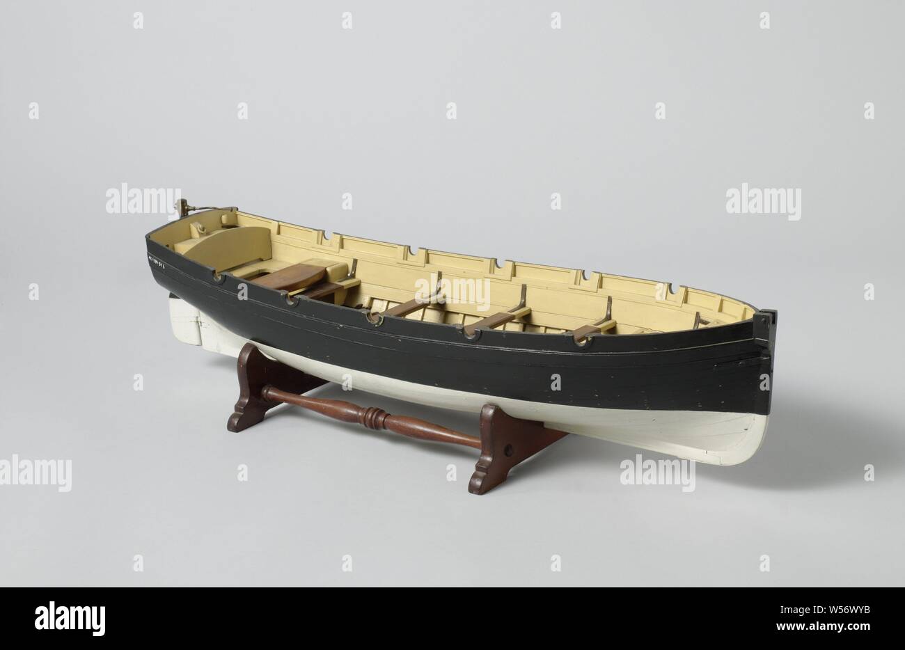 Model of a Longboat, Polychromed truss model on a standard. Smooth-edged double-belted bark, curved with almost flat sheer and flat mirror, disc in the prow, a forecourt, five dulls and four rails, and an open cabin with side depths and extra loose doft. Simple rudder with a curved brass tiller to get around the grape mast. 1:10 scale (derived)., anonymous, Netherlands, c. 1865 - c. 1880, wood (plant material), brass (alloy), model: h 16.4 cm × l 63 cm × w 19.8 cm packaging capsule: h 21 cm × w 65 cm × d 24 cm Stock Photo