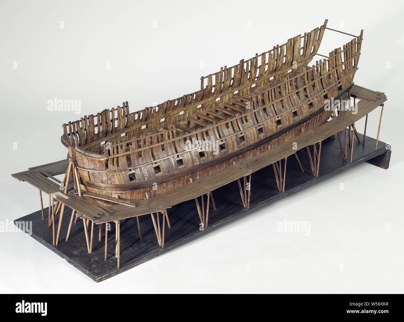 Scaffolding Model of a 60 to 68-Gun Ship, Truss model of the hull of a ship on a slope surrounded by wooden scaffolding, on a sloping ground board. The skin of the model has been omitted so that the nine-part frames are visible. As far as can be distinguished, the model has sixty-six artillery gates divided over three decks, which are only indicated by the gates, except for the lower deck, for which deck beams are also fitted. Twisted mirror with two gates, hollow wulf, no fence details or side galleries. The sheer runs slightly to both ends, a bar wood. Flat round. Striking is the replacement Stock Photo