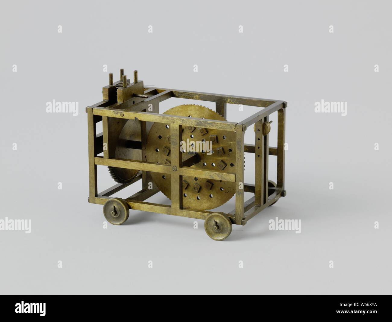 Model of a Cart for Rope Making, A cart for rope-making, consisting of a brass frame on wheels, equipped with a wheel. The large wheel of the gear is arranged in the longitudinal direction and has a large number of holes for supports arranged in concentric circles, on which rope is rolled up. The trolley only has one swivel hook., anonymous, Netherlands, c. 1800 - c. 1825, brass (alloy), iron (metal), h 14.8 cm × w 16.6 cm × d 12.5 cm Stock Photo