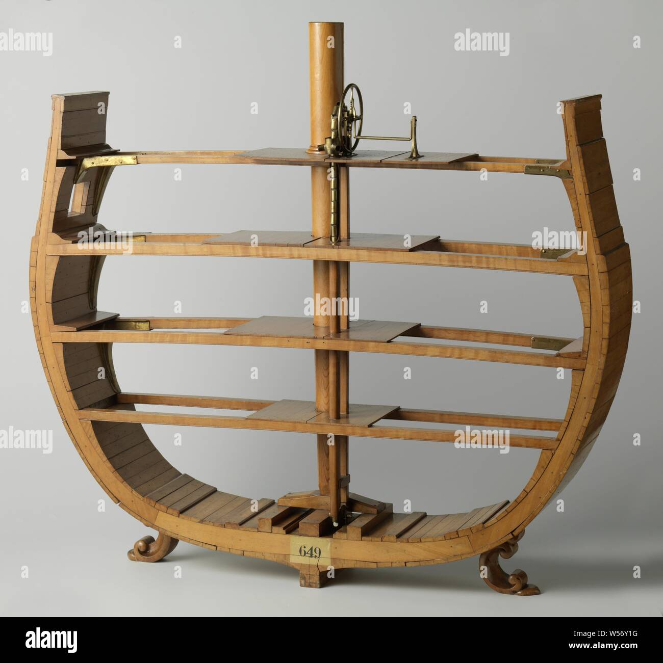 Model of a Chain Pump, Model of the cross-section of a ship at the height of the large mast, with four decks and a chain pump. The pump consists of a chain of buckets that are guided down a pump tube down to the keel and come up again along another tube, on the upper deck they go over a pentagonal wheel that is driven by a crank and flywheel. The four decks are partially planked and supported by deck beams that feature eight different hollow metal knees: some are nailed to the wooden knee that they cover, others to the weighing, some to the deck beam, others to the deck boards. 1:20 scale Stock Photo