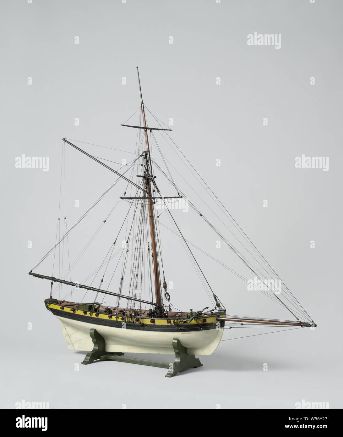 Model of a 20-Gun Cutter, Polychromed, witnessed block model of a 20-piece cutter. It has eighteen pieces (two missing) on the open deck. The prow is bent. Flat mirror, hollow wulf polychrome painted with draperies, closed fence polychrome painted with sitting woman with anchor for sea with ship, straight rudder with square rudder king and tiller on deck, strong falling stern. The sheer rises slightly to both ends, one barwood. The underwater ship is a sharp peaked round truss with a large steering load. The model is equipped with two anchors, a roasting spindle, two pumps and different Stock Photo