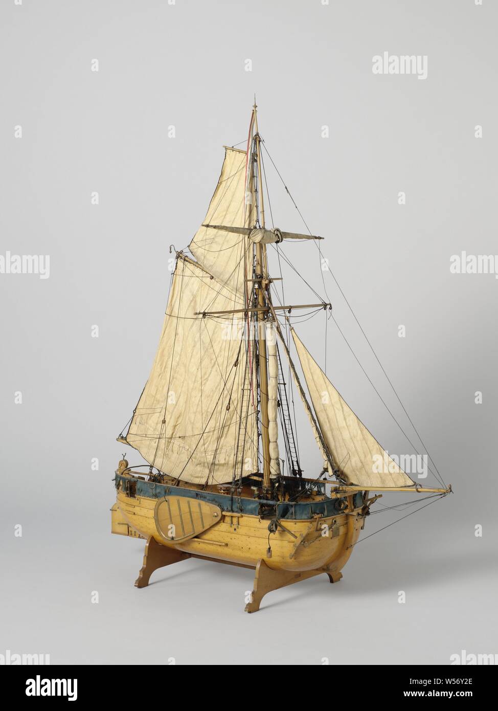 Model of a Gaff-Rigged Gunboat, Testified eroded block model of a single-mast flat-bottomed gunboat, incomplete. Round bow and stern, a port in the bow, two in the stern, four in the sides. The deck is detailed with a roasting spindle, a chimney for the galley, hatches, a deck, a compass house, two pumps, ten cannon balls and two anchors. All around a gown, four forks on the back and four poles on either side for a raised gown. Below deck not worked out. Wide rudder with decorated rudder head and wooden tiller over the deck. Flat sheer, a bar wood, swords. The model is rigged with a single Stock Photo
