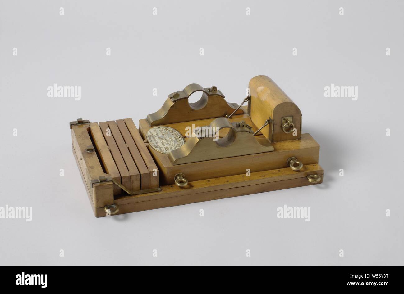Model of the Bed of a 20-cm Sea Service Mortar on a Pivoting Undercarriage, Model of a mortar chair for mortar of 20 inches (cm) on swivel bed. The swivel bed consists of a flat wooden plate with a hole for the spindle bolt in the middle. At the rear is a fixed buffer beam with five removable beams, which serve as a buffer for absorbing the recoil, small spools are arranged between these beams, alternately at the ends or in the middle, through which the beams can spring. The chair consists of two parts placed in the direction of the layers and has taps made entirely of brass, a trough for Stock Photo