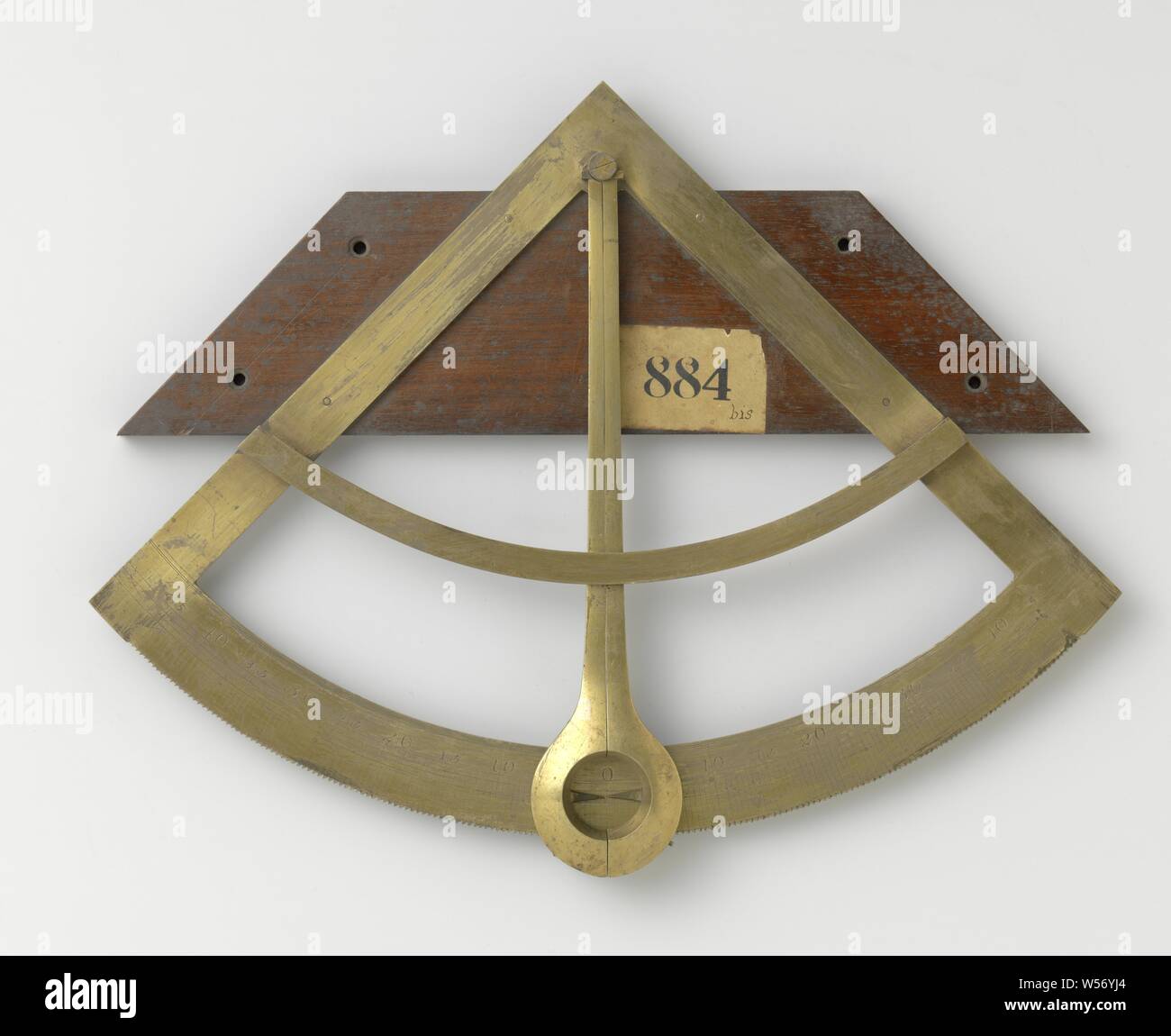 Quadrant, Two almost identical clinometers to measure the maximum slope of a swinging ship. Both are brass, mounted on a wooden back plate with the center of the bow at the top. The scale on the arc runs from 0 ° to 45 ° each side. The outer edge of the arc is toothed, each side in the opposite direction. The two hands have catches on the back, which engage in the teeth: they can only move outwards along the arch. The catches can be released by hand to bring the hands back to 0 °. A slight interruption of the ratchet edge prevents the hands from falling into each other's eighth of the arc. Stock Photo