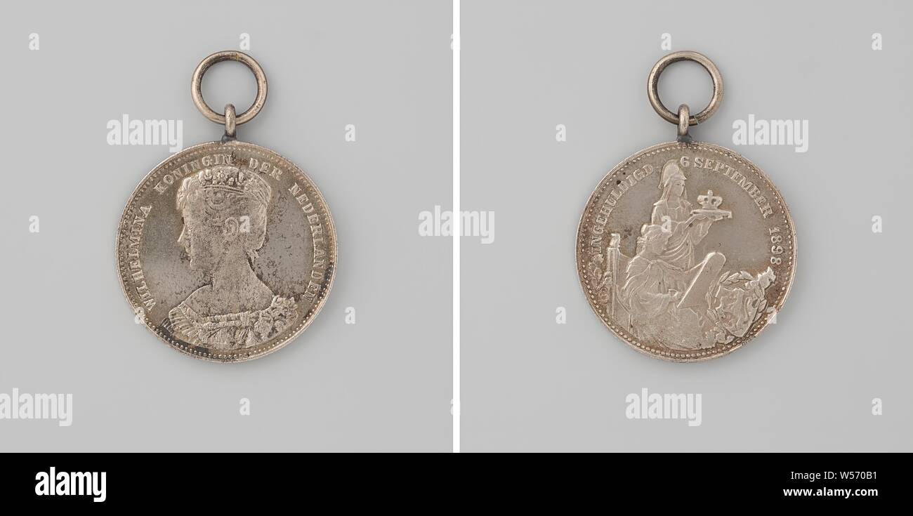 Inauguration of Wilhelmina as queen of the Netherlands, medal awarded to school children, Copper medal to the eyebolt and ring. Obverse: bust of a woman with a diadem inside the inscription. The other side: helmeted woman, representing the Netherlands, holds in her outstretched hands a cushion on which lies a crown, in front of her is History, who writes with pen on the tableau, in the foreground on the right a coat of arms surrounded by laurel branches, with orange ribbon in bottom of matching black box with gold lettering, Amsterdam, Wilhelmina (Queen of the Netherlands), Johannes Albertus Stock Photo