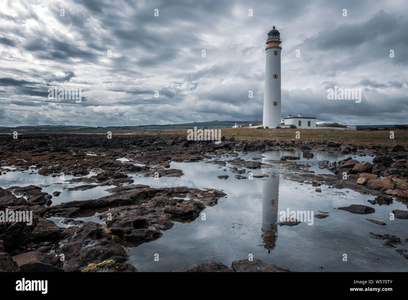 UK Landscapes: Creative image of Barns Ness Lighthouse reflected in a rock pool with dramatic sky,  East Lothian, Scotland Stock Photo