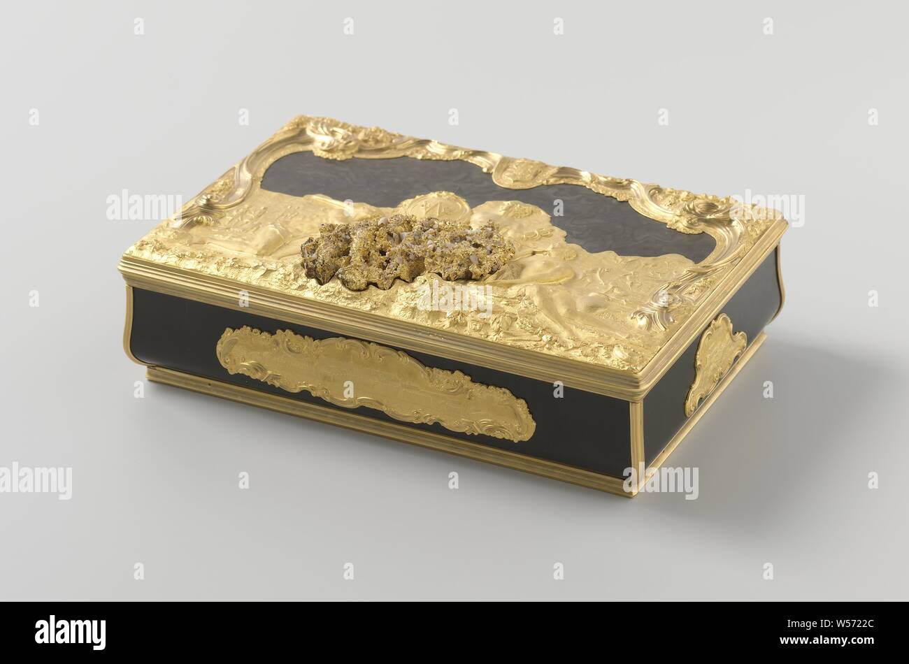 Box of the Dutch West India Company, The trade of the West India Company in Africa, Rectangular box of turtle and gold, The rectangular box, with rounded corners, has a loose lid. Bottom, walls and lid are made of turtle, set in profiled golden edges. The lid contains a gold nugget with white stones, around which a scene with Mercury as the God of Commerce in the center, on the right a woman washing gold with on her right a scene with gold diggers, and on the left a man wearing an elephant stand, with a scene on his left on the coast depicting the trade in slaves. In the middle at the top Stock Photo