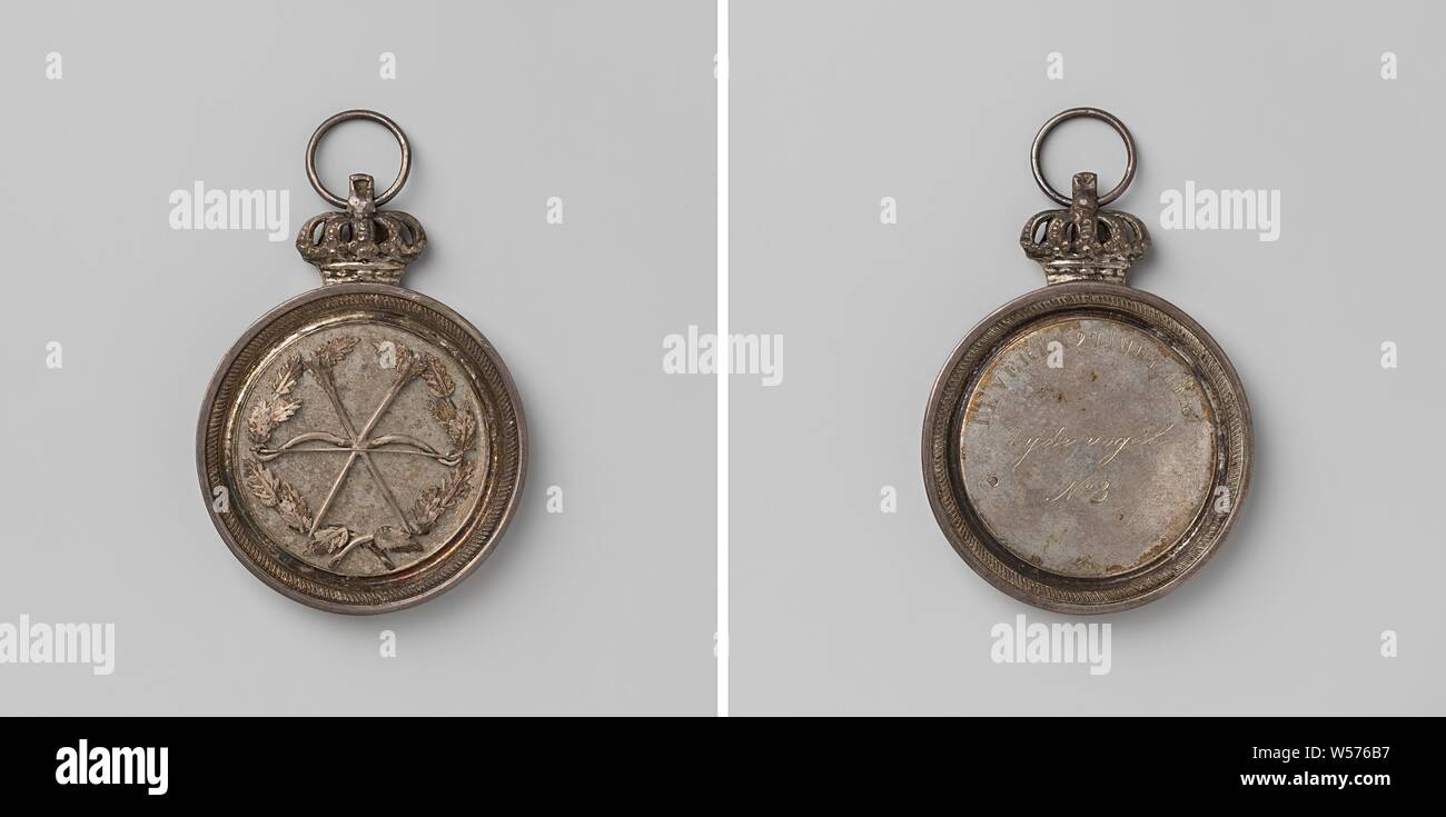 Gaaischieten in Beveren, medal with inscription 'silk bird no. 3 ', Silver medal consisting of two round plates mounted in a ring, attached to an openwork crown on the supporting ring. Obverse: in relief: two crossed arrows on an arch within an oak wreath. Reverse: inscription inside the inscription, in the reverse side field two nails, with which both sides are joined together, Beveren, anonymous, Belgium, 1847, silver (metal), founding, h 6.2 cm × d 4.7 cm × w 18.85 Stock Photo