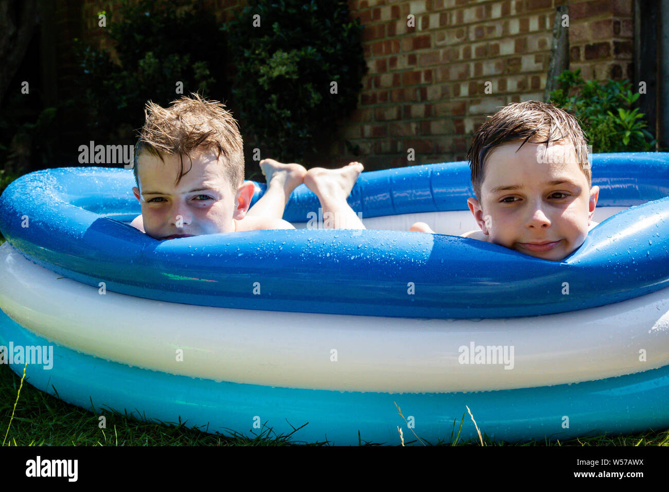 Preteen boys laying in a paddling pool Stock Photo