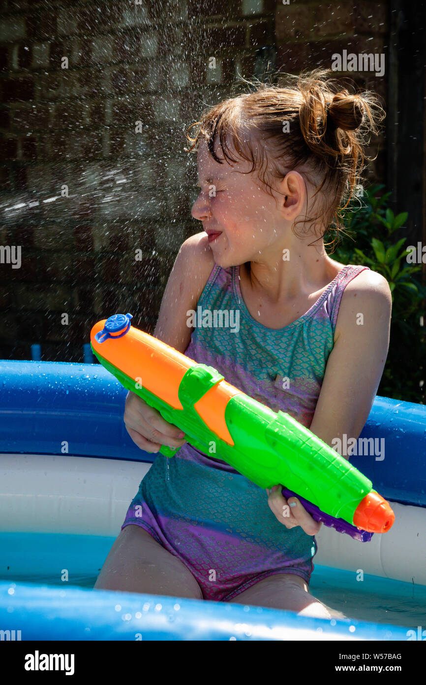 Preteen caucasian girl playing wth a water gun on a hot summer's day Stock  Photo - Alamy
