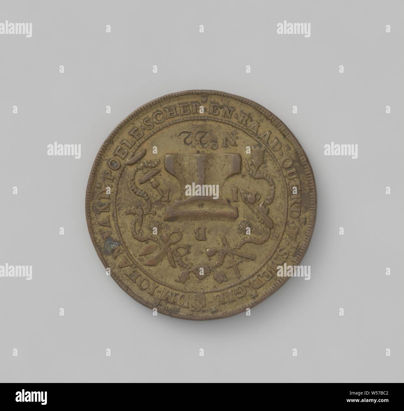 Blacksmith's Guild of Middelburg, guild token with no. 22, Brass token. Front: anvil surrounded by the letters I, B and K, around it a chain, on which hang a lantern, gun lock, daggers, gun, scissors, balance and candlestick, below: number 22 within a circle. Reverse: crowned front hammer between years, surrounded by a chain, on which two crossed buses, a horseshoe, an anchor, a door lock with a key, a shaft and a boiler hang within a circle, Middelburg, Johan van de Poele, Jans. van den Drissen, Am. Rickaart, Har. van Vollenhoo, P. Hack, Willem du Pre, 1690, brass (alloy), engraving, d 4.7 cm Stock Photo