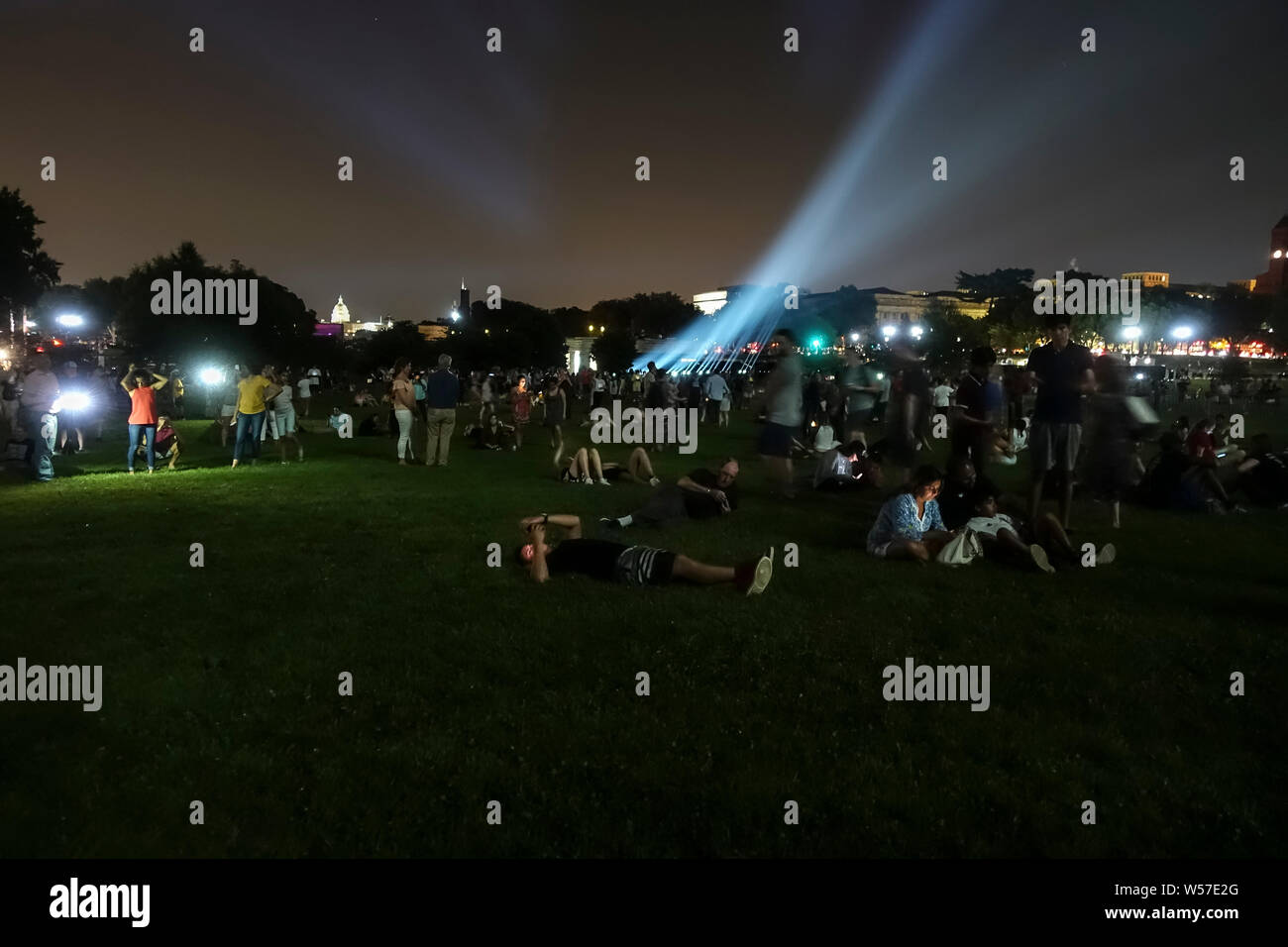 Washington, DC - July 18, 2019. Celebrating the 50th anniversary of the first lunar landing, tourists and locals gaze up at an image of the Saturn V rocket which is projected onto the Washington Monument, part of a five-day commemorating the Apollo 11 moon landing in 1969. Stock Photo