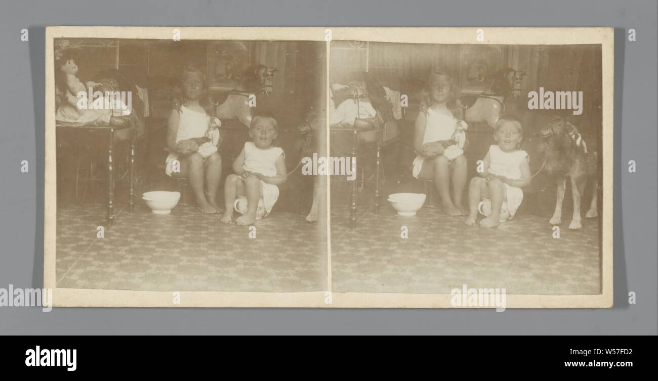 Two children in pots surrounded by toys, chamber-pot, playing toddler, child amusing itself, interior of the house, anonymous, c. 1910 - c. 1920, cardboard, photographic paper, h 88 mm × w 178 mm Stock Photo
