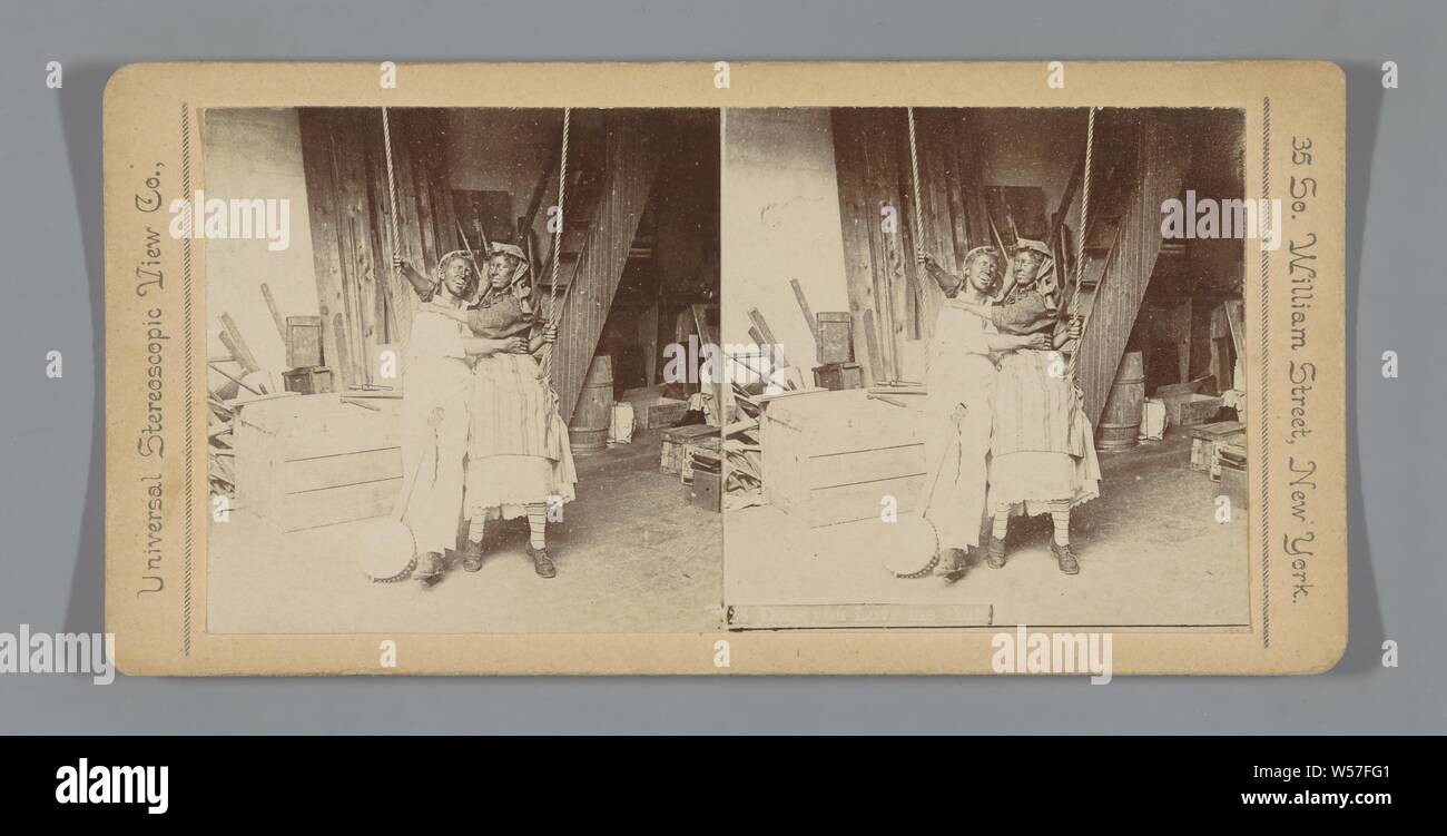 Couple with black painted faces on a swing, Does you Love me Hun, couple of lovers, painting of body or face, swing, Universal Stereoscopic View Company (mentioned on object), c. 1890 - c. 1920, photographic paper, cardboard, h 88 mm × w 178 mm Stock Photo