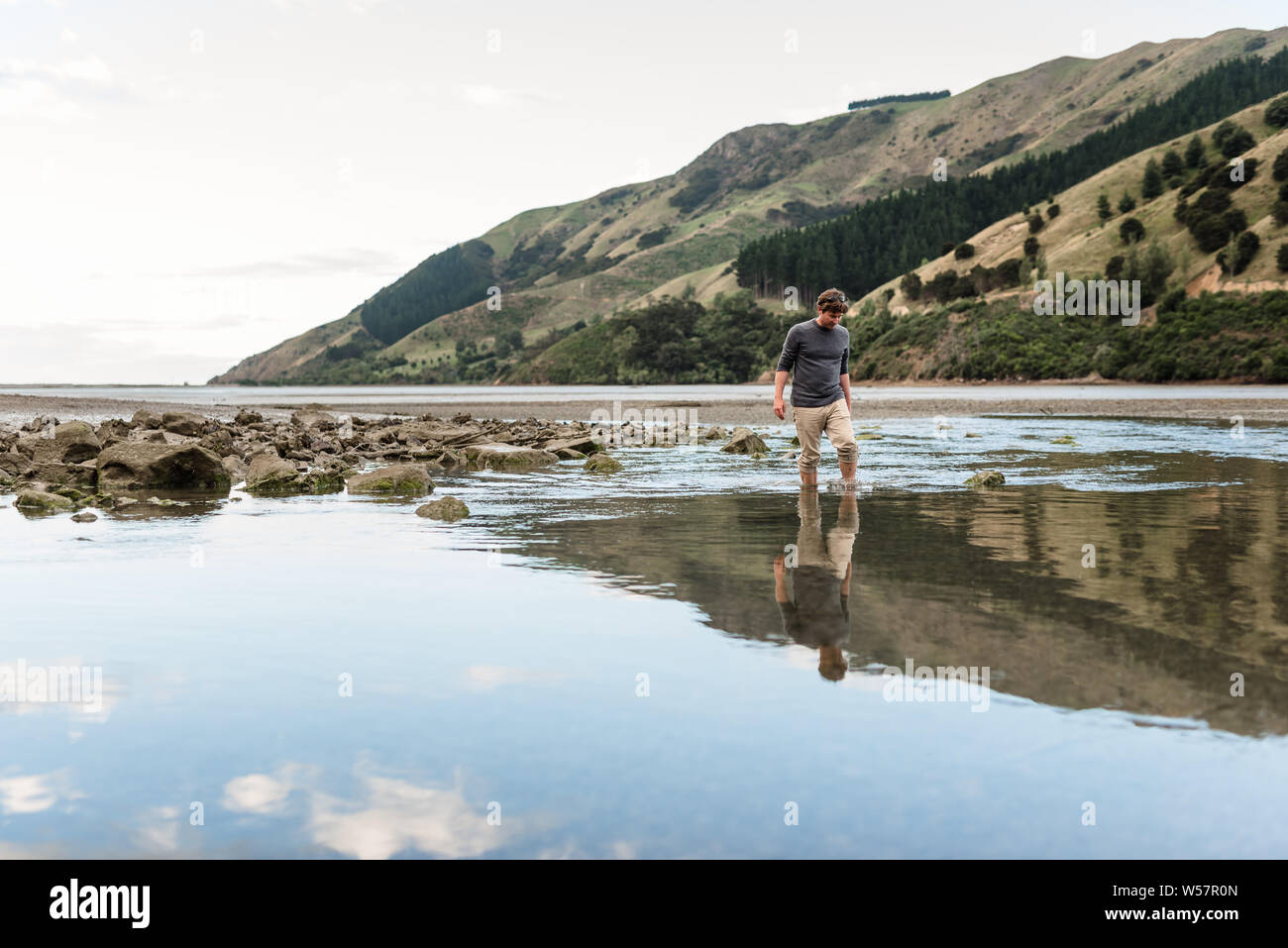 Man walking in estuary at low tide Stock Photo