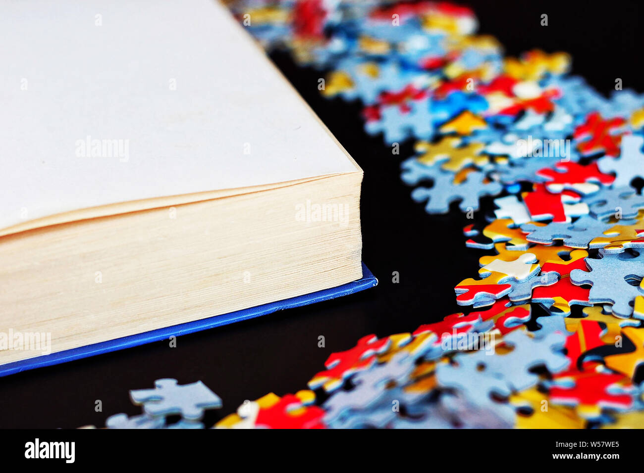 Book next to some puzzle pieces. Stock Photo