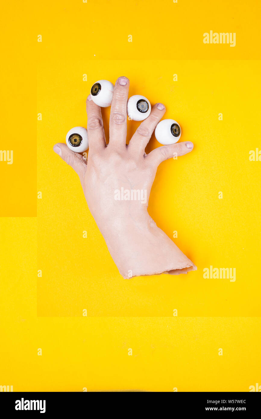 plastic hand with 4 eyes between your fingers Stock Photo