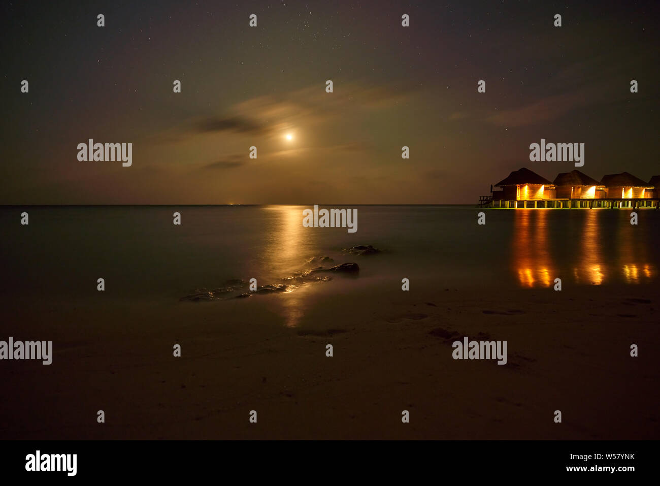 Beautiful sunset, Dark with the moon shinning on the smooth surface of the sea and rocks in Kandolhu island Maldives 2019 Stock Photo