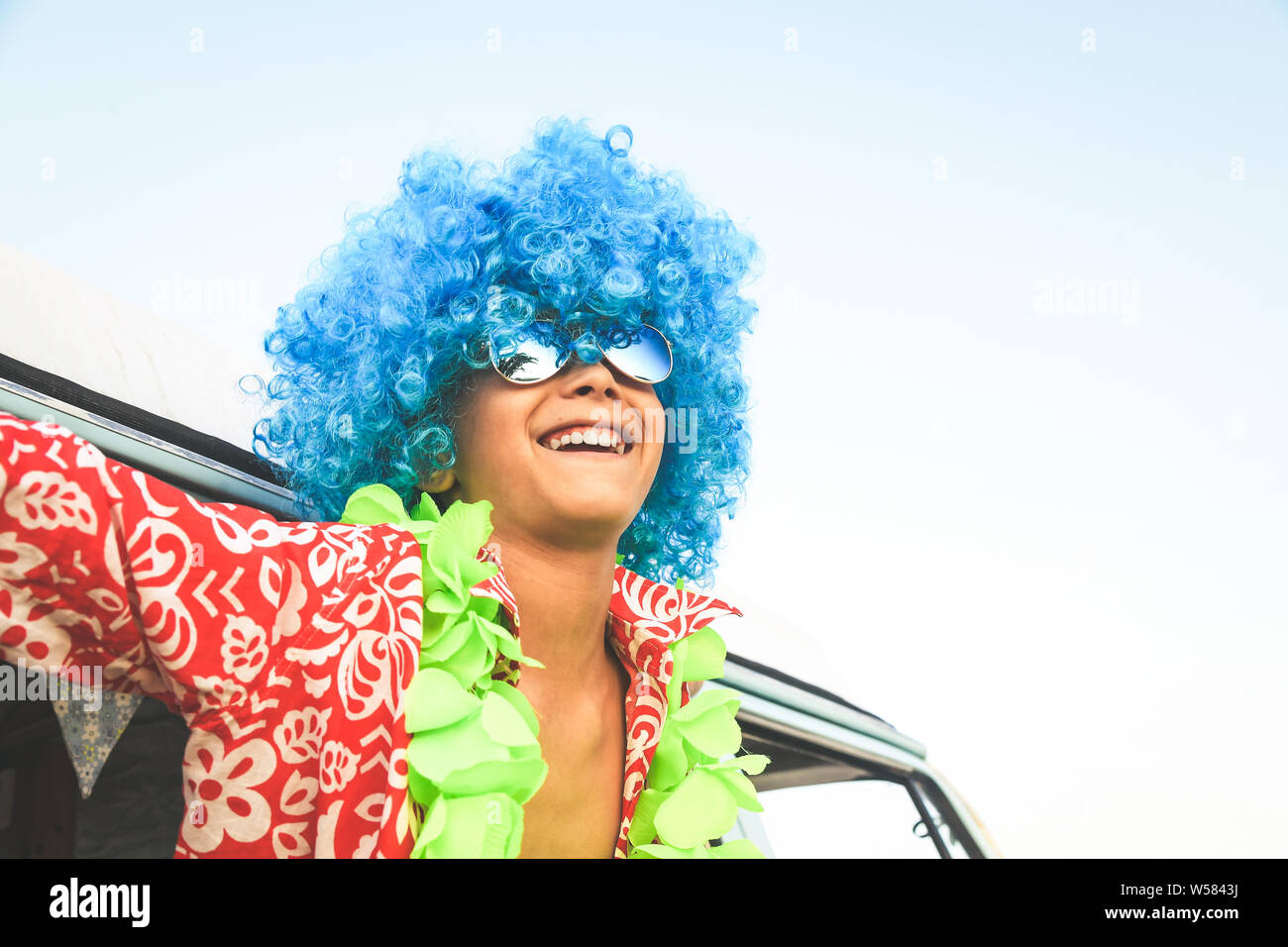 Crazy funny young man with blue wig red shirt with white flowers
