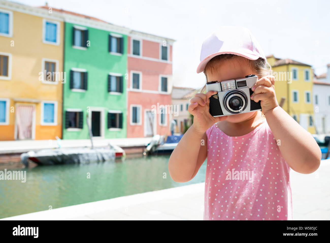 Little Girl Taking A Picture On Camera With Colorful Houses At Backdrop In Burano Island Stock Photo
