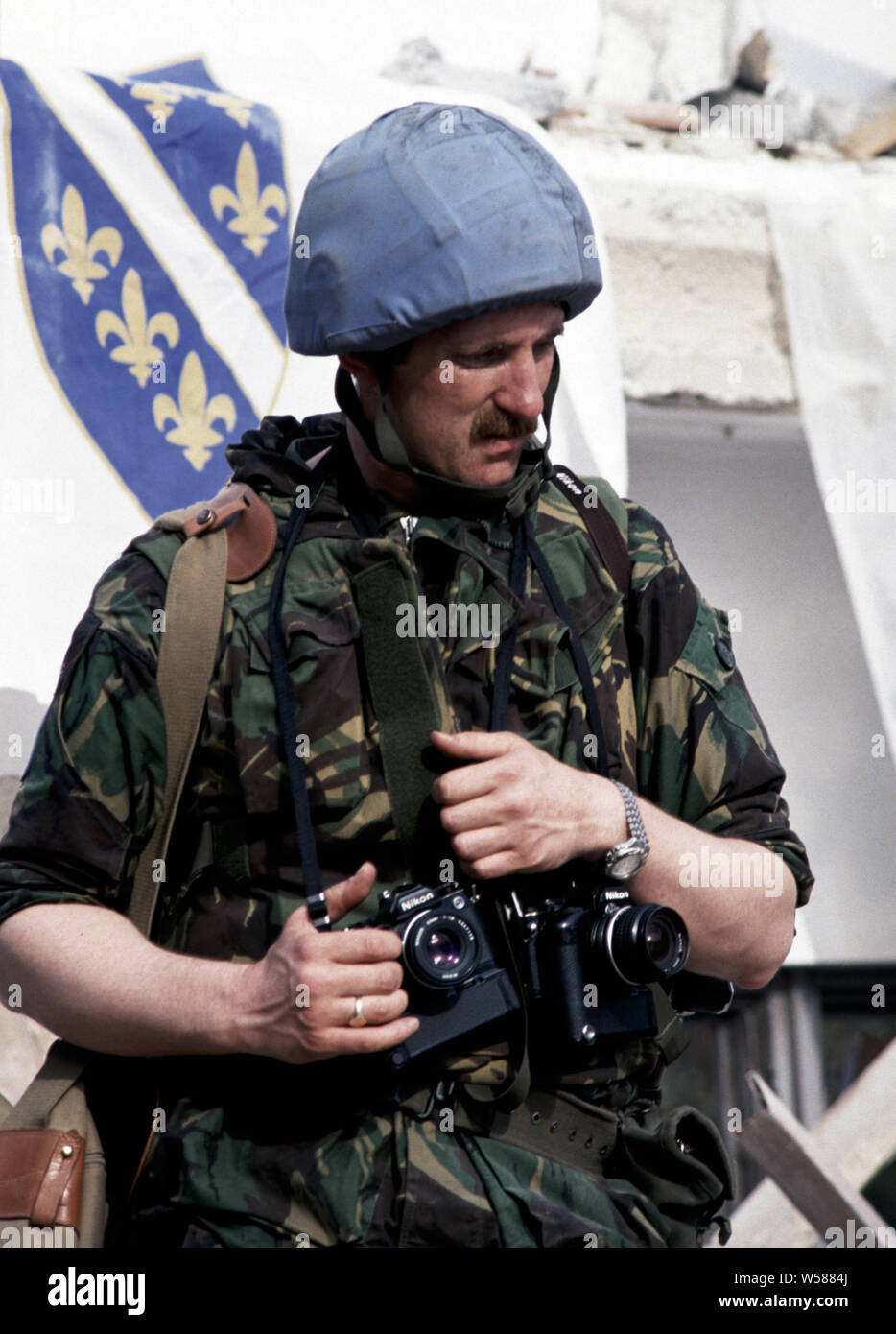 25th April 1993 During the war in Bosnia: in Stari Vitez, a British Army  photographer, a couple of Nikon F3 cameras around his neck, stands in the  rubble of the Bosnian War