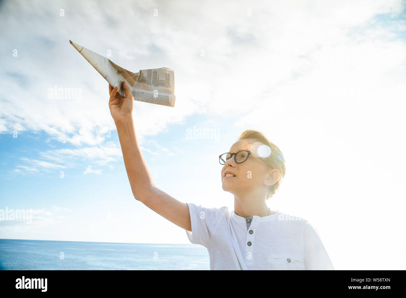 Happy child playing with paper airplane at sunset, dreaming about ...