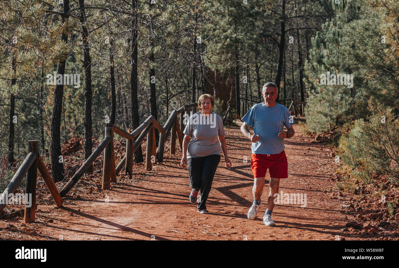 Couple active senior running outside in green nature Stock Photo