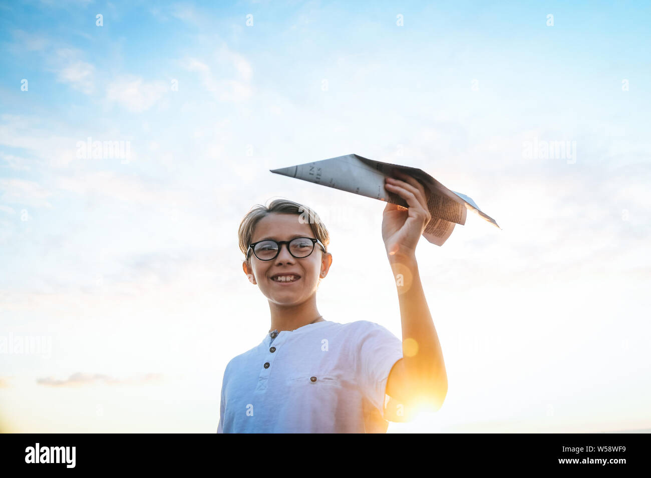 Happy child playing with paper airplane at sunset, dreaming about ...