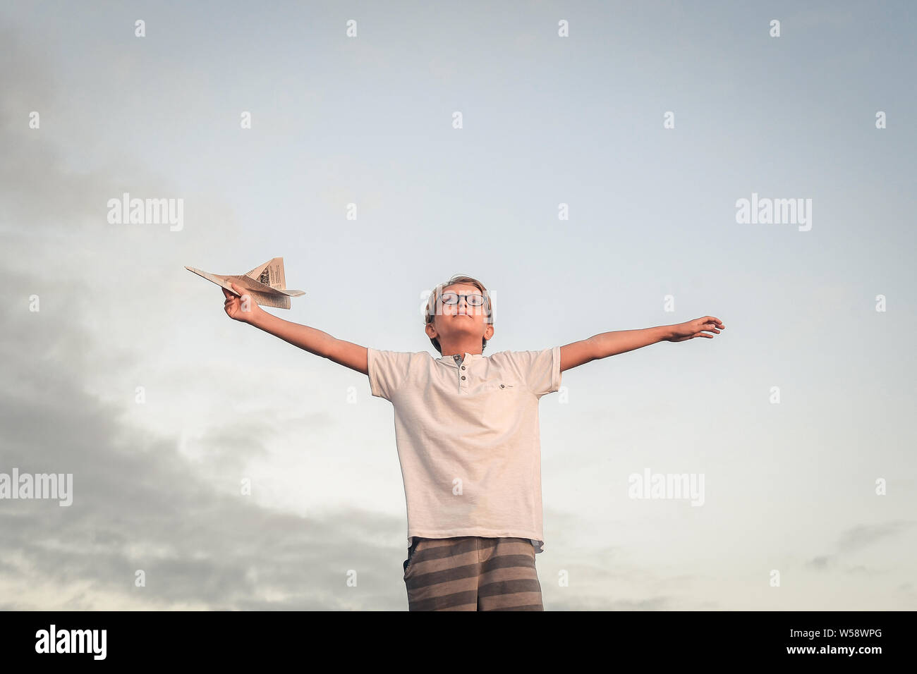 Happy child playing with paper airplane at sunset, dreaming about ...
