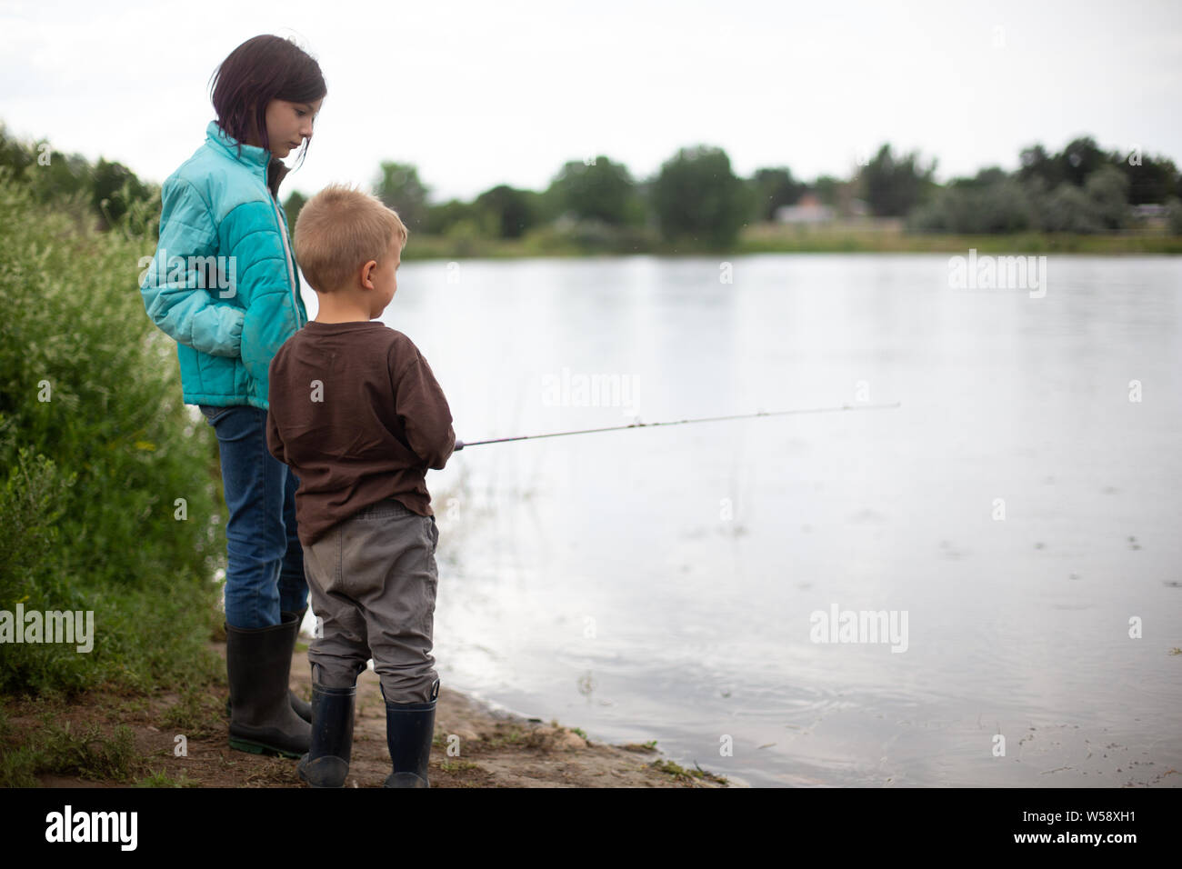 Big sister helping little brother fishing Stock Photo