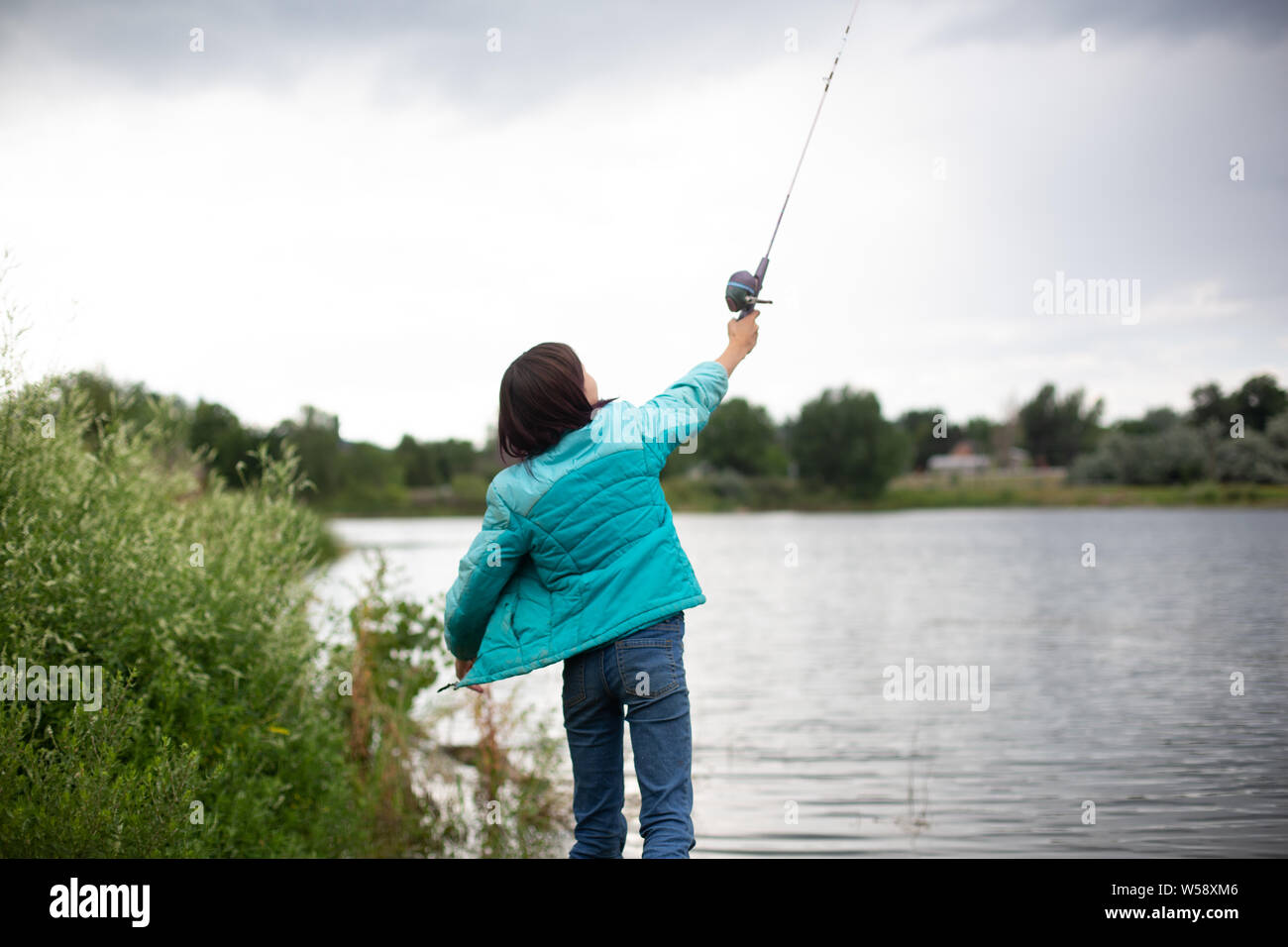 Girl casting fishing line over her head Stock Photo - Alamy
